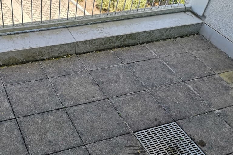 Reinigung von Terrassenplatten auf einem Balkon im ersten Stock
