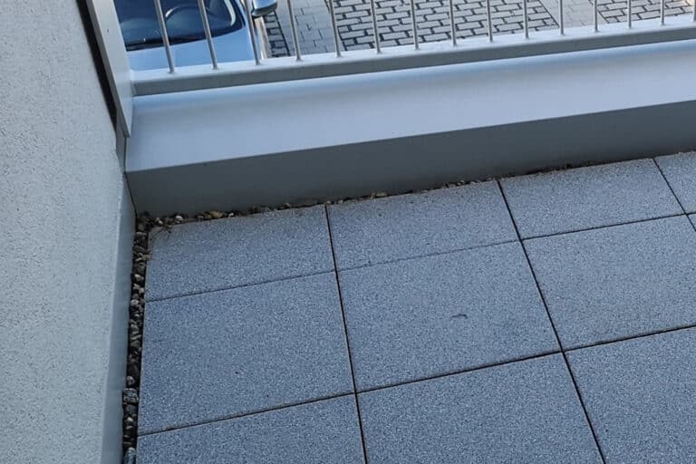 Reinigung von Terrassenplatten auf einem Balkon im ersten Stock